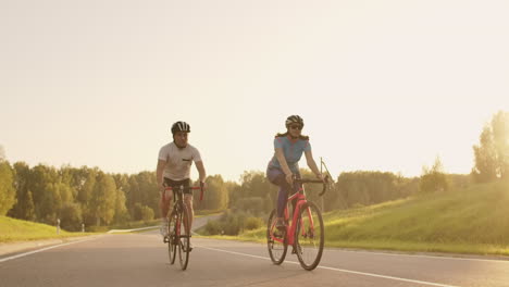 Steadicam-Aufnahme-Eines-Mountainbike-Paares,-Das-Bei-Sonnenuntergang-In-Luftiger-Höhe-Auf-Einem-Radweg-Unterwegs-Ist.